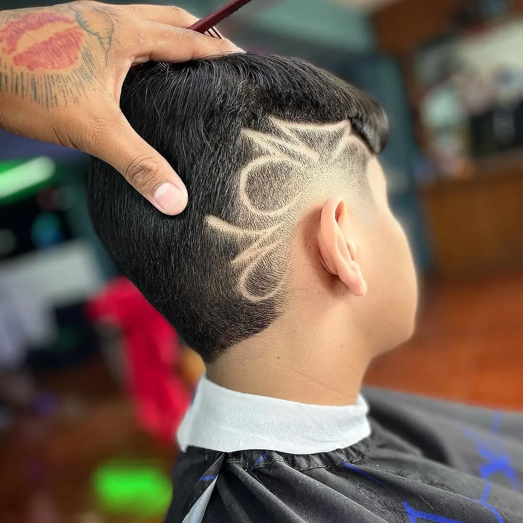 Joven visto de lado con burst fade y un diseño freestyle de líneas curvas grandes dibujado en el costado de la cabeza