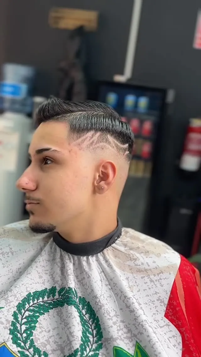 Joven de perfil con corte francés peinado de lado, raya marcada y diseño de líneas curvas en el fade de la sien