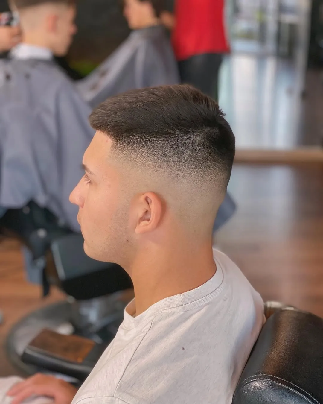 Joven de perfil en barbería con crop corto arriba y desvanecido alto en los lados