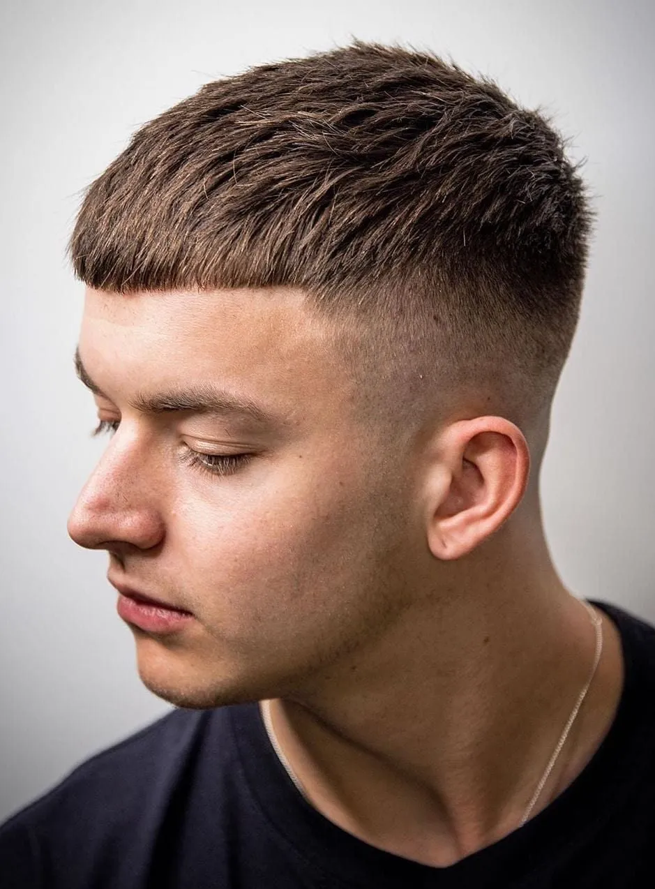 Joven con French crop con fleco recto corto y desvanecido alto, fondo gris claro