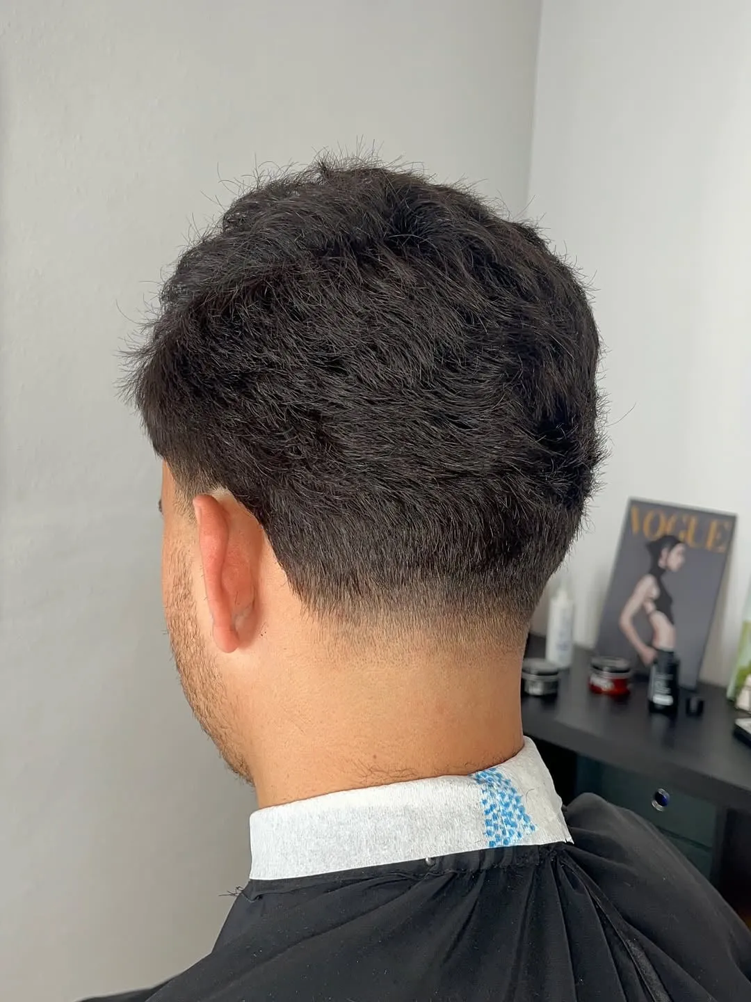 Low taper fade visto de espaldas con la nuca desvanecida y cabello texturizado arriba