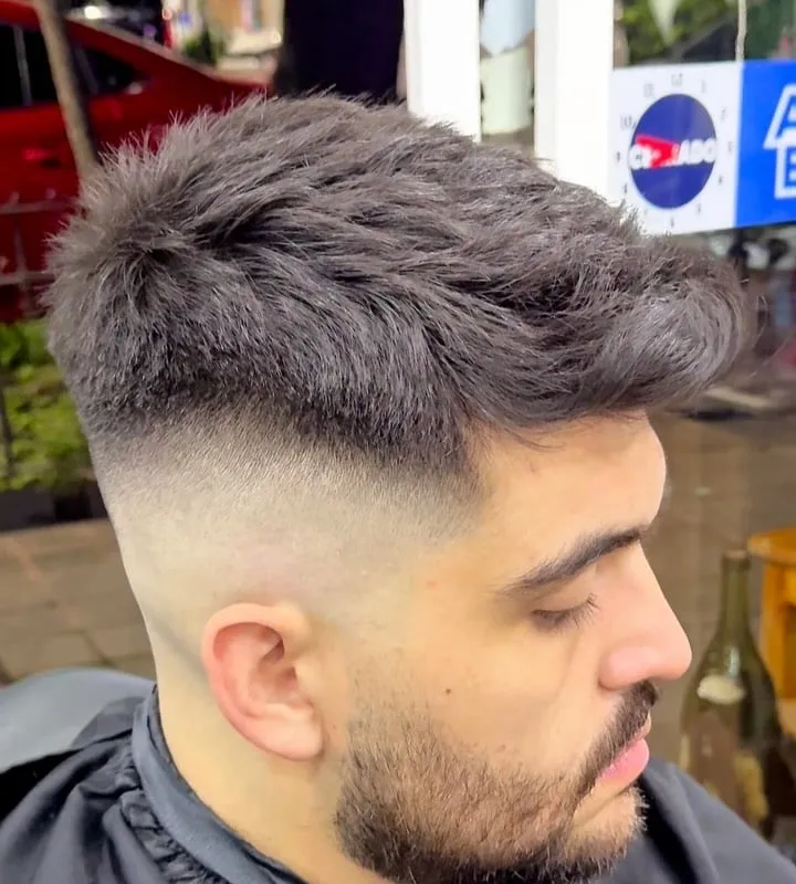 Hombre con quiff texturizado alto y desvanecido alto en las sienes, barba corta