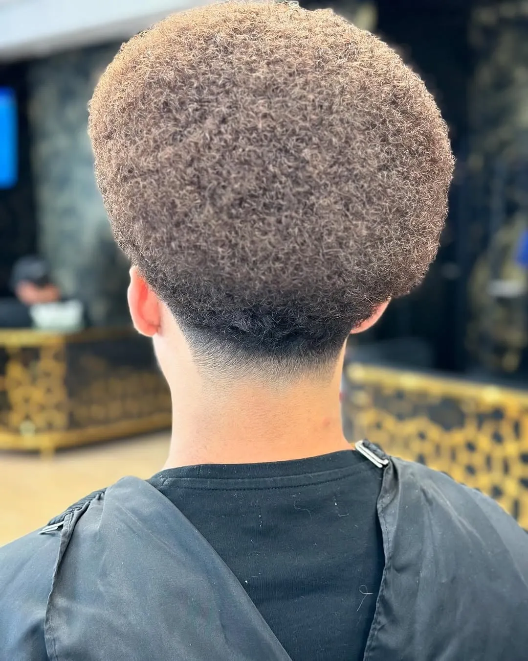 Taper fade en cabello afro redondo visto de espaldas con la nuca desvanecida