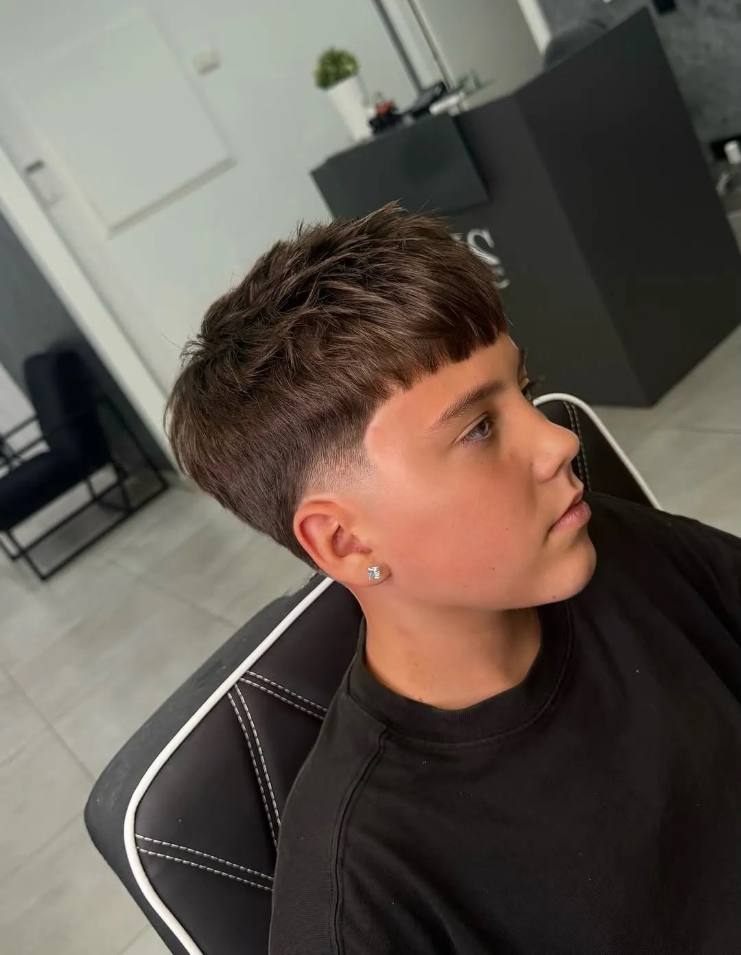 Taper fade medio con fleco recto tipo edgar en cabello castaño visto de perfil