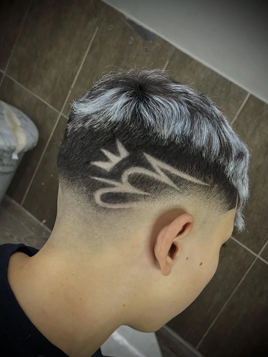 Desvanecido con diseño de corona y líneas freestyle en el costado sobre cabello negro con puntas platinadas