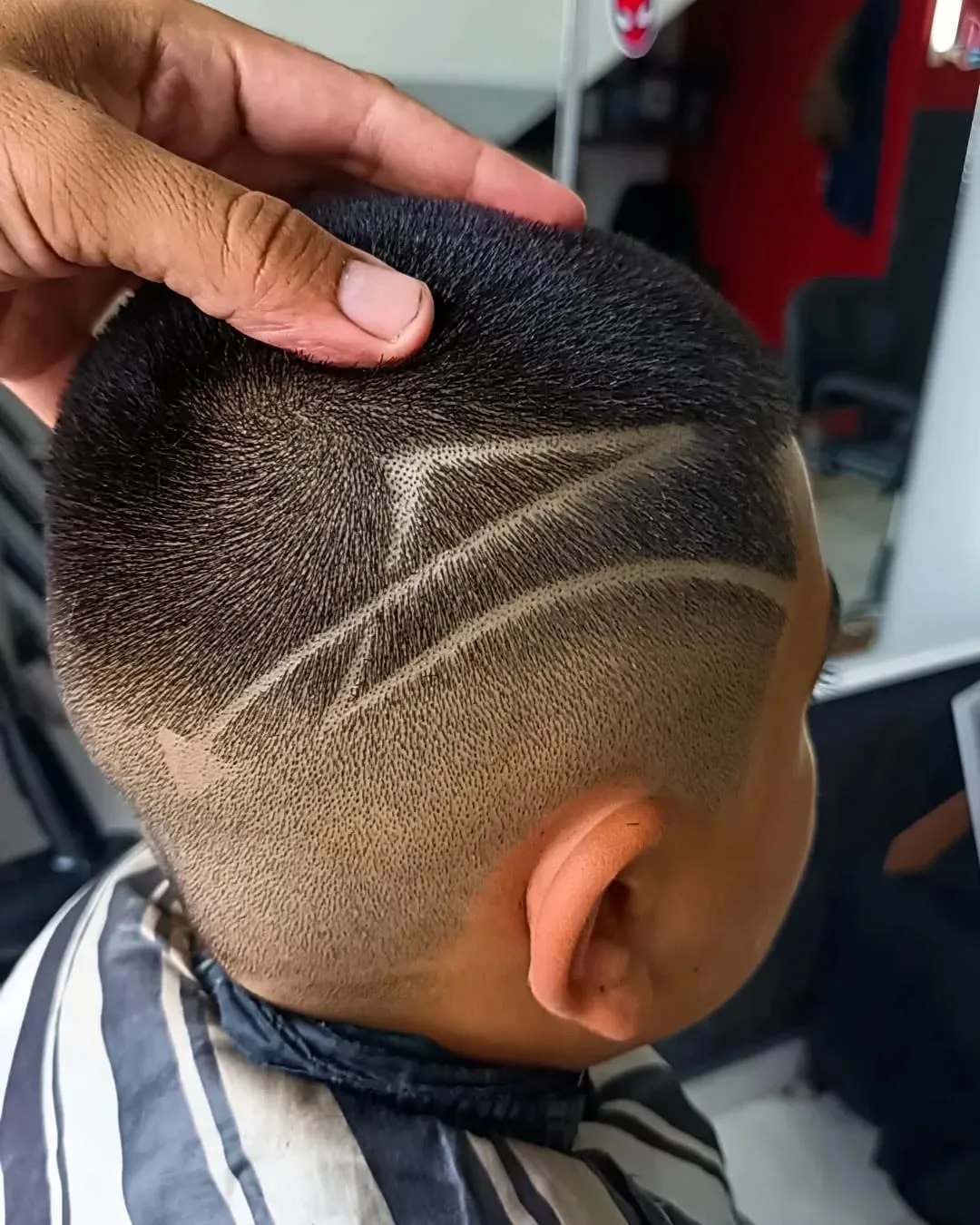 Desvanecido con diseño de flecha formado por líneas largas en diagonal sobre la oreja en cabello negro corto