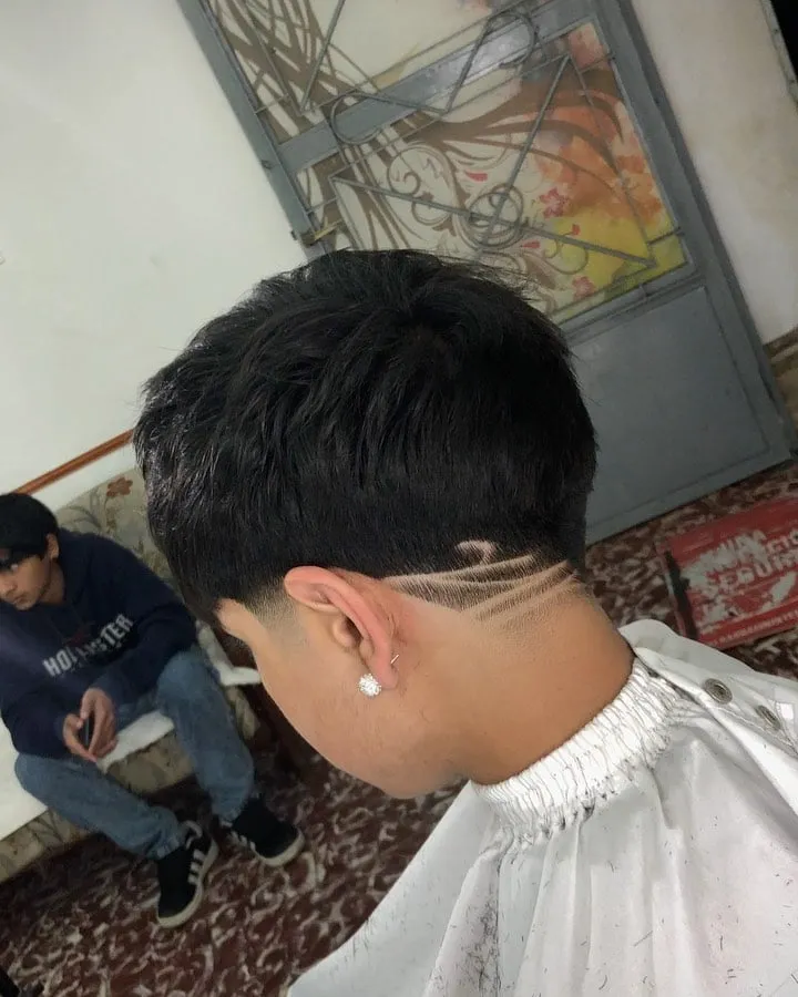 Taper fade bajo con dos líneas rectas en el costado sobre la oreja y cabello negro lacio