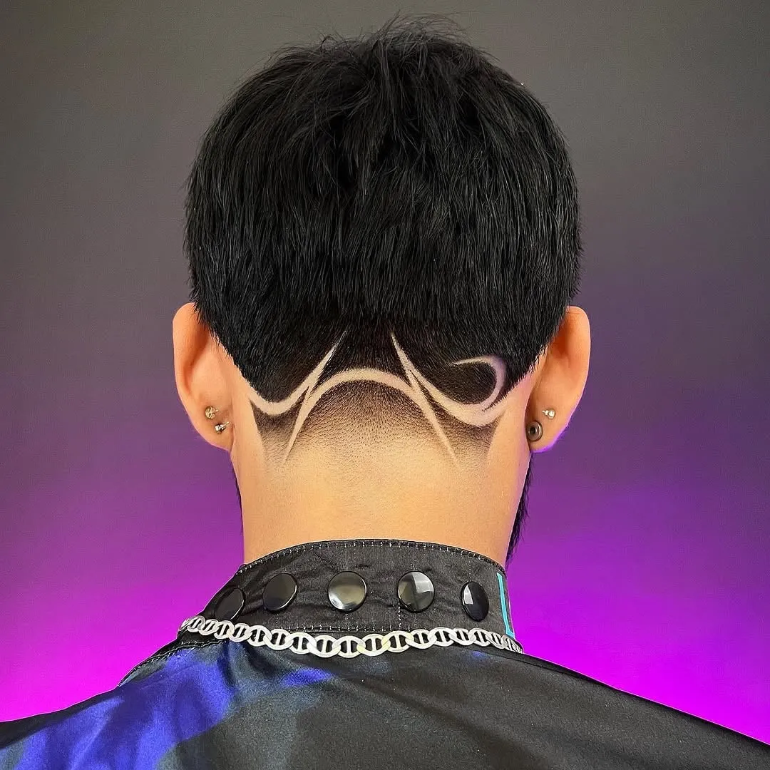 Taper fade visto de espaldas con un diseño de líneas curvas simétricas en la nuca y cabello negro corto arriba