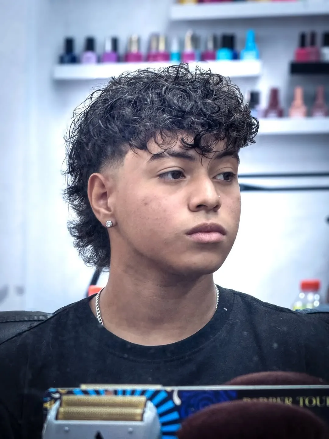 Taper fade con mullet en cabello rizado oscuro, largo atrás y fleco con rizos al frente