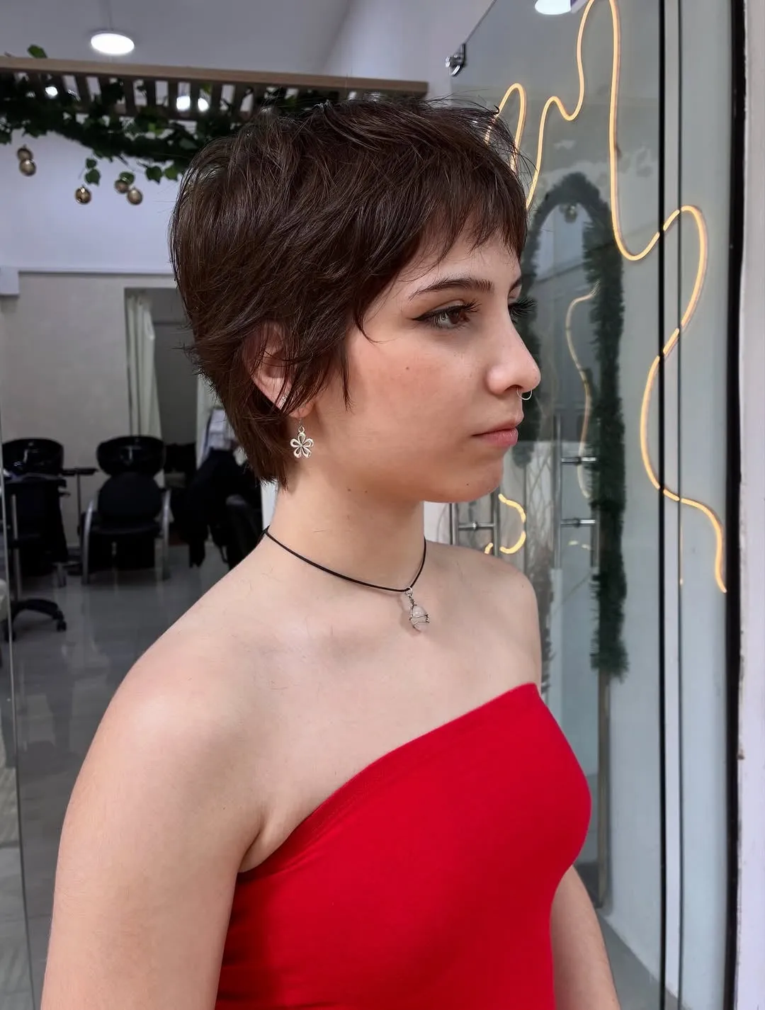 Mujer joven de perfil con wolf cut muy corto en cabello castaño oscuro, capas texturizadas y nuca algo más larga