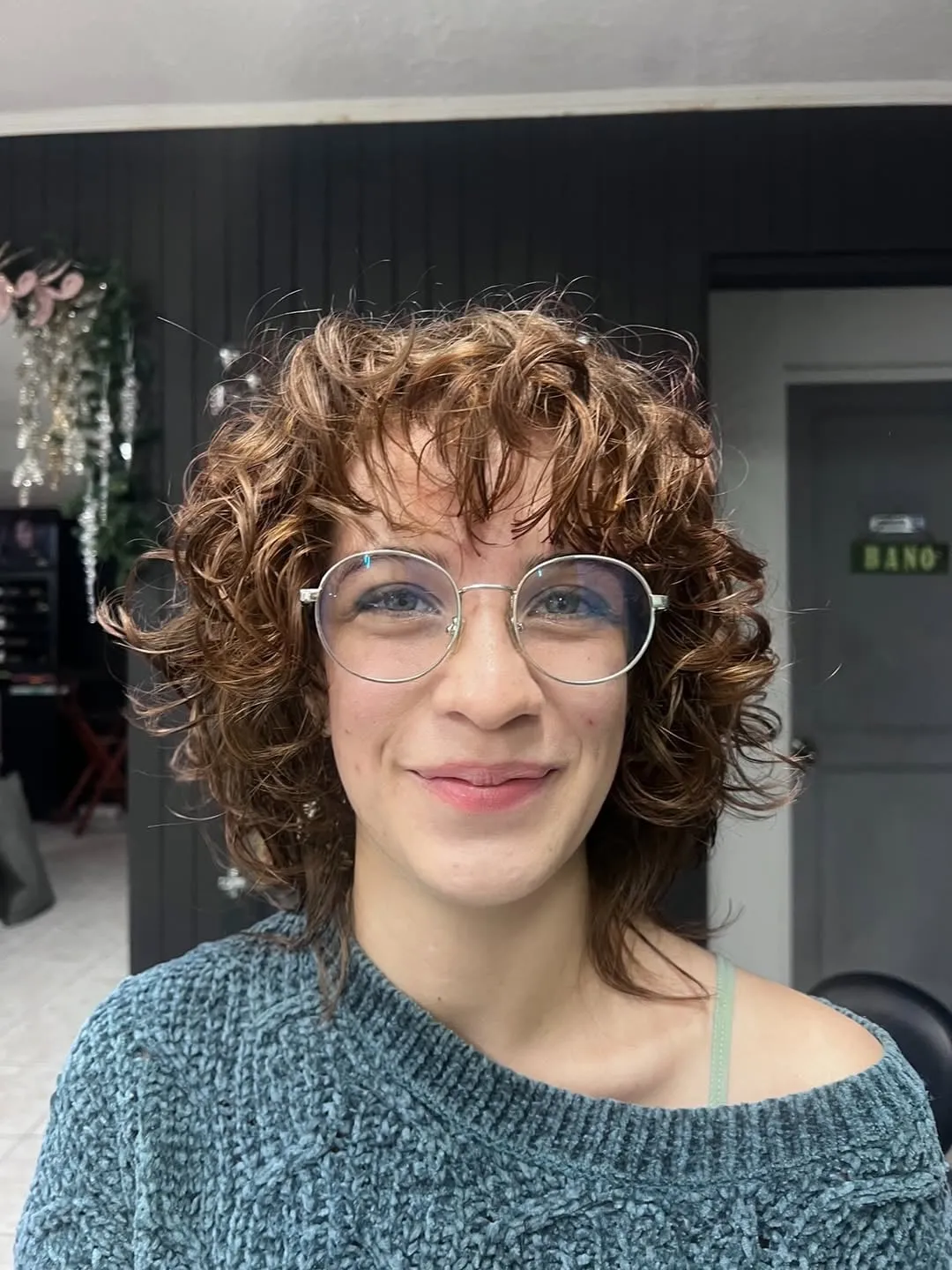 Mujer con lentes y wolf cut rizado corto castaño, rizos pequeños con volumen en la coronilla y flequillo rizado