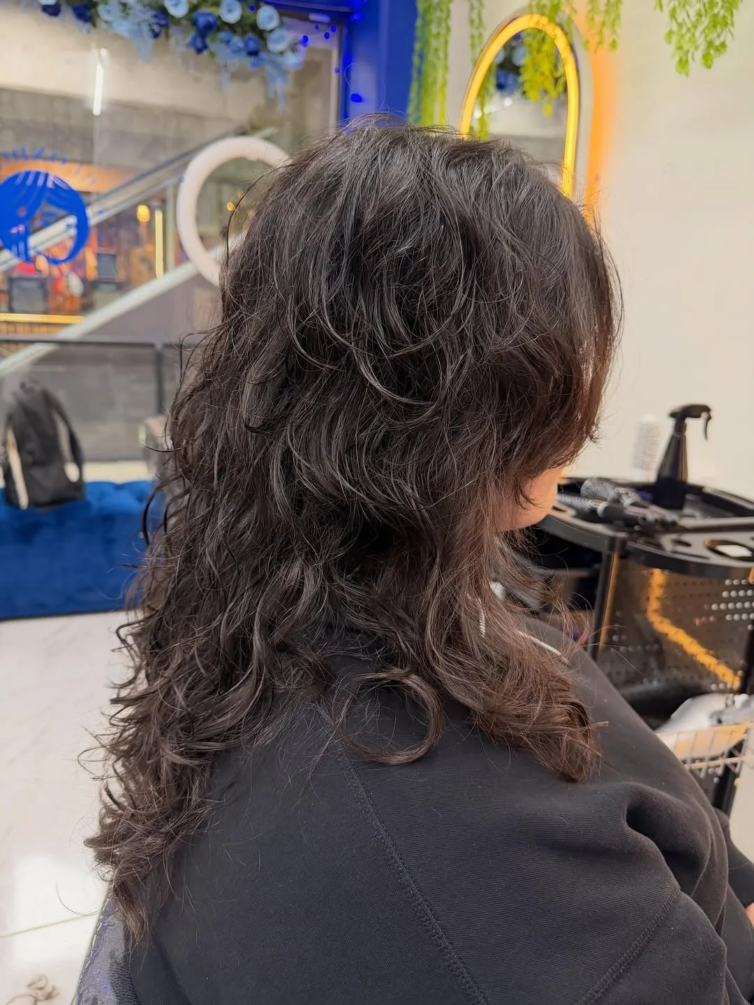 Mujer de espaldas con wolf cut largo en cabello castaño ondulado, capas cortas en la coronilla y nuca desfilada en mechones largos